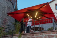 Abendliches Treffen unter einem beleuchteten roten Sonnenschirm