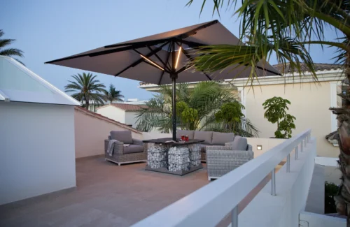 Moderne Dachterrasse mit stilvollen Möbeln und großem Sonnenschirm bei Abenddämmerung